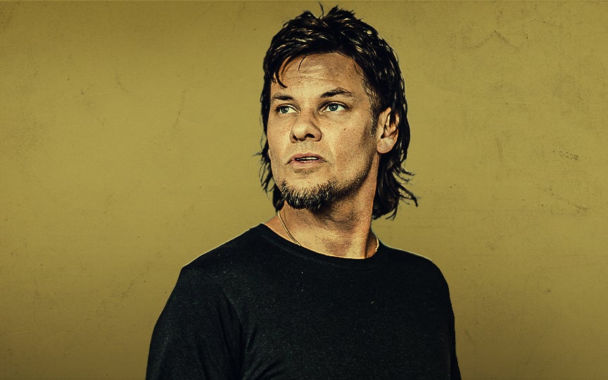 Theo Von with short hair and a goatee looking to the side